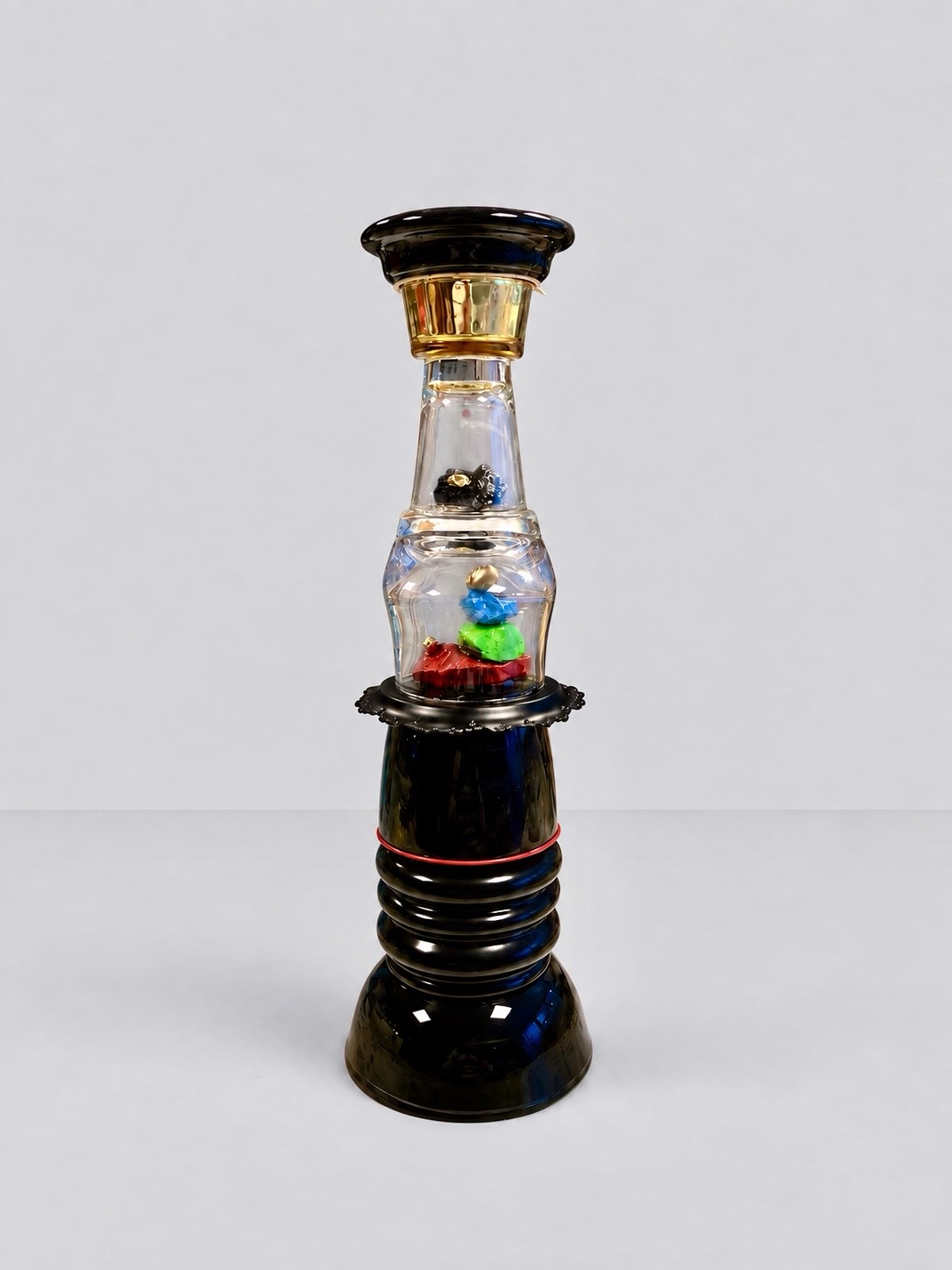 Red and green painted rocks beneath glass on a black base