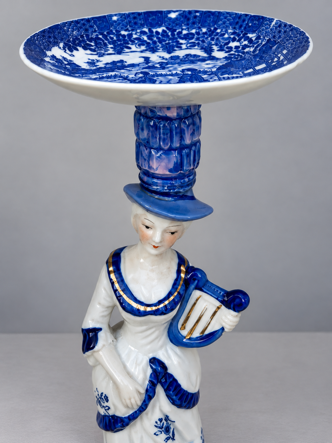 Close view of the porcelain muse and blue glass in the candleholder
