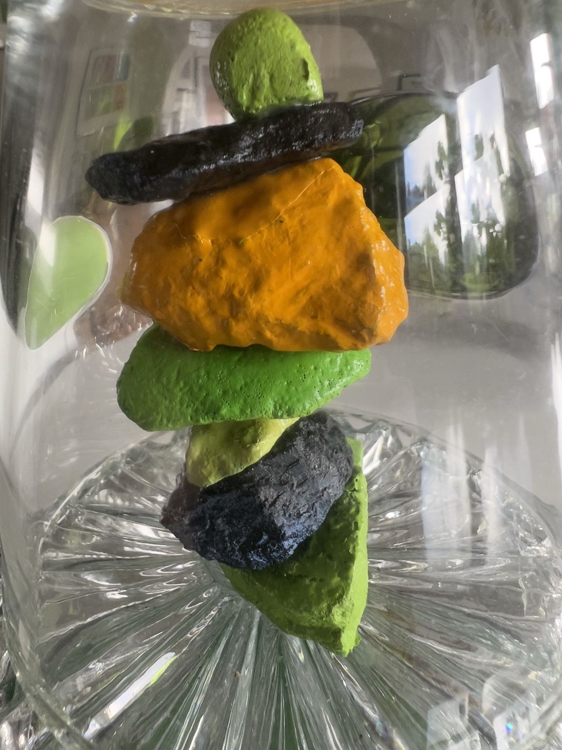 Close view of orange, green and black painted rocks beneath clear glass