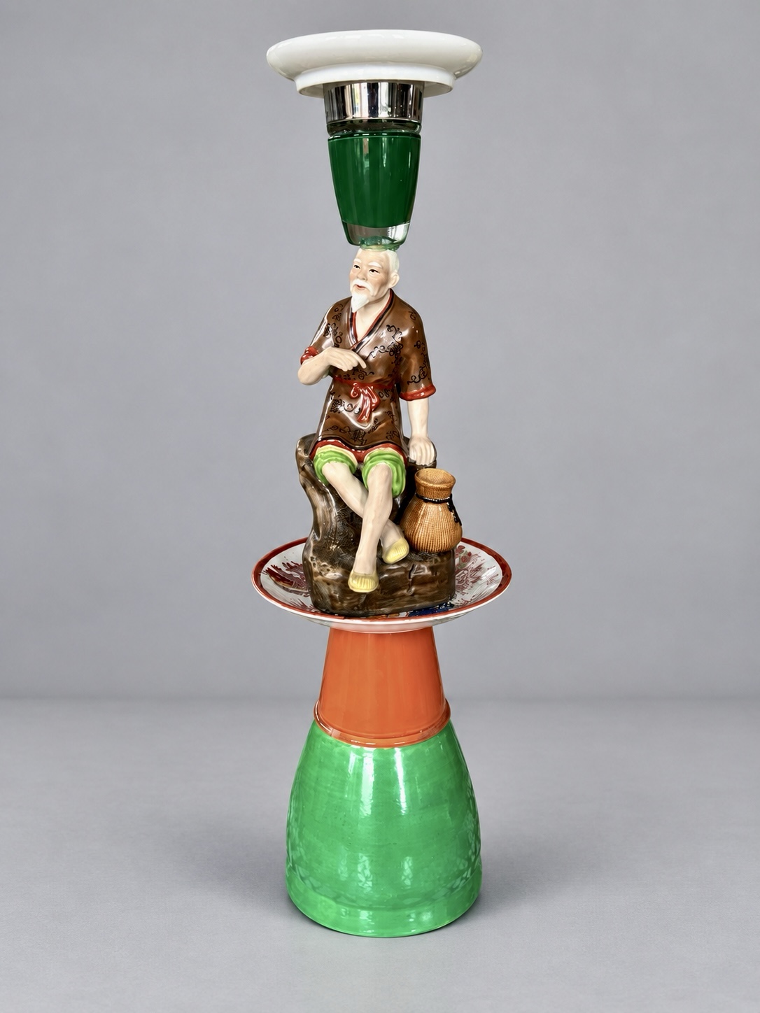 Tall green and orange assemblage candleholder with a seated porcelain old man