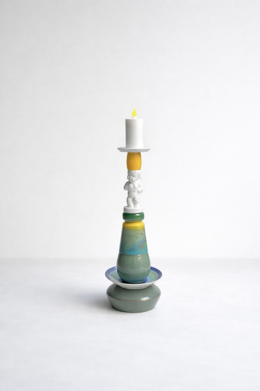 Small white porcelain boy within a green, yellow and pale-blue assemblage candleholder