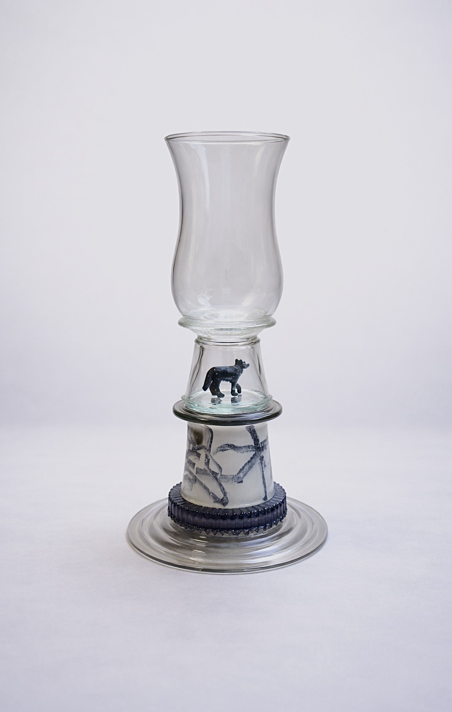 Clear glass assemblage with a small dark wolf enclosed beneath the upper vessel